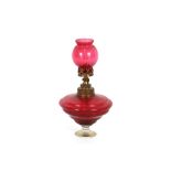 An unusual cranberry glass lace makers lamp, raised on clear glass foot, 27cm high