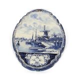 A Delft plaque, depicting winter canal scene with barges and windmills, cartouche shape, 60cm x 67cm