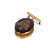 A late Victorian black enamel and yellow metal locket brooch, with monogrammed decoration