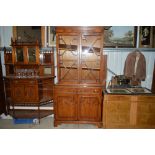 A reproduction yew wood and glazed bookcase raised