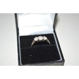 A white metal dress ring set with three white ston