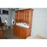 A modern pine and glazed dresser raised on cupboard