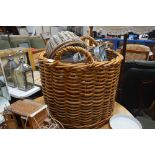 A large wicker log basket; a metal bottle carriers
