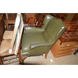 A green leather wing back armchair raised on carve