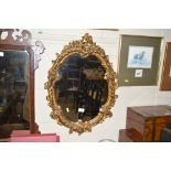 An ornate gilt plaster oval wall mirror