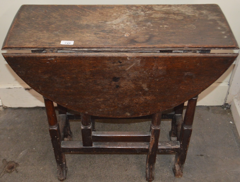 An 18th Century oak gate leg table, raised on turned supports terminating in Braganza type feet,