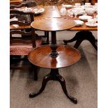 A George III mahogany two tier dumb waiter, raised on baluster turned column and tripod base,