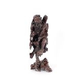 A Chinese carved hardwood figure of an immortal, with staff and beast on pierced leaf base, 55cm