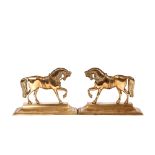 A pair of Victorian brass horse doorstops, with coloured glass eyes raised on stepped bases, 30cm