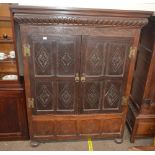 An antique oak hanging press cupboard, enclosed by a pair of lozenge carved panelled doors,