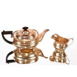 A George V silver teapot, and matching cream jug, baluster shape with gadrooned borders, raised on