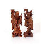Two carved Oriental hardwood figures, of immortals with staffs and baggage, 30cm high