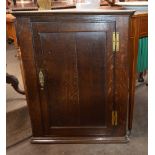 An antique oak hanging corner cupboard, the interior shelves enclosed by a single moulded panel