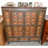 An ornate painted Tibetan side cabinet the upper and lower sections enclosed by pairs of pinned