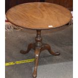 A George III mahogany circular tea table, the tilting dish top raised on a turned baluster column
