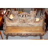 An 18th Century continental pine carved bench, decorated Putti and trailing foliage raised on scroll
