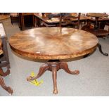 A 19th Century circular walnut dining table, the radially veneered snap top raised on a turned