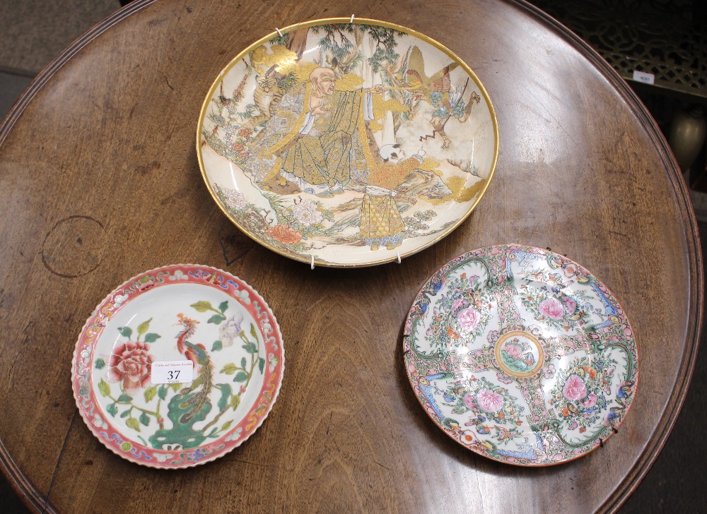 A Satsuma plate, decorated central mystical figures in a forest - some damage; a Canton plate