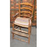 An antique elm child's ladder back high chair, rush seat above foot rest on turned supports united