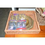 A wicker tray and contents of brass embossed plaqu