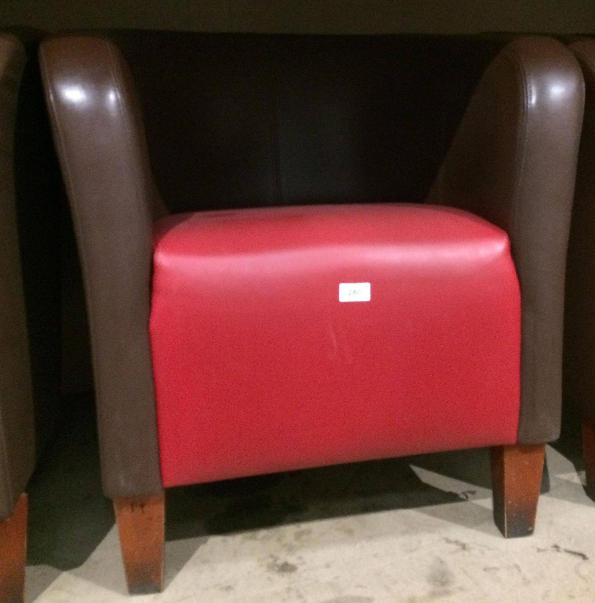 Brown and red vinyl upholstered tub chair on dark wood feet