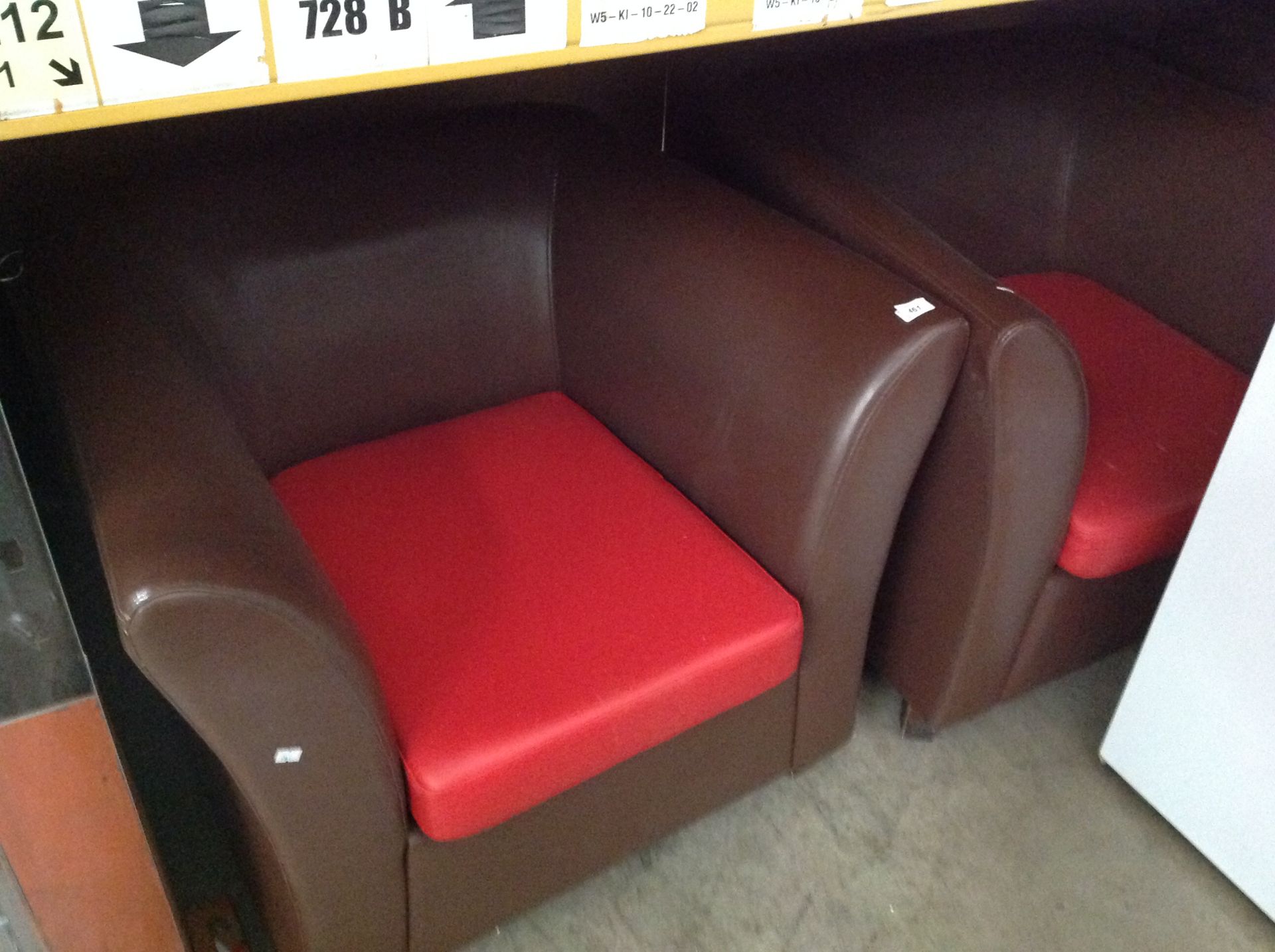 A pair of chocolate brown vinyl upholstered curved arm armchairs with red vinyl seats (one with bad