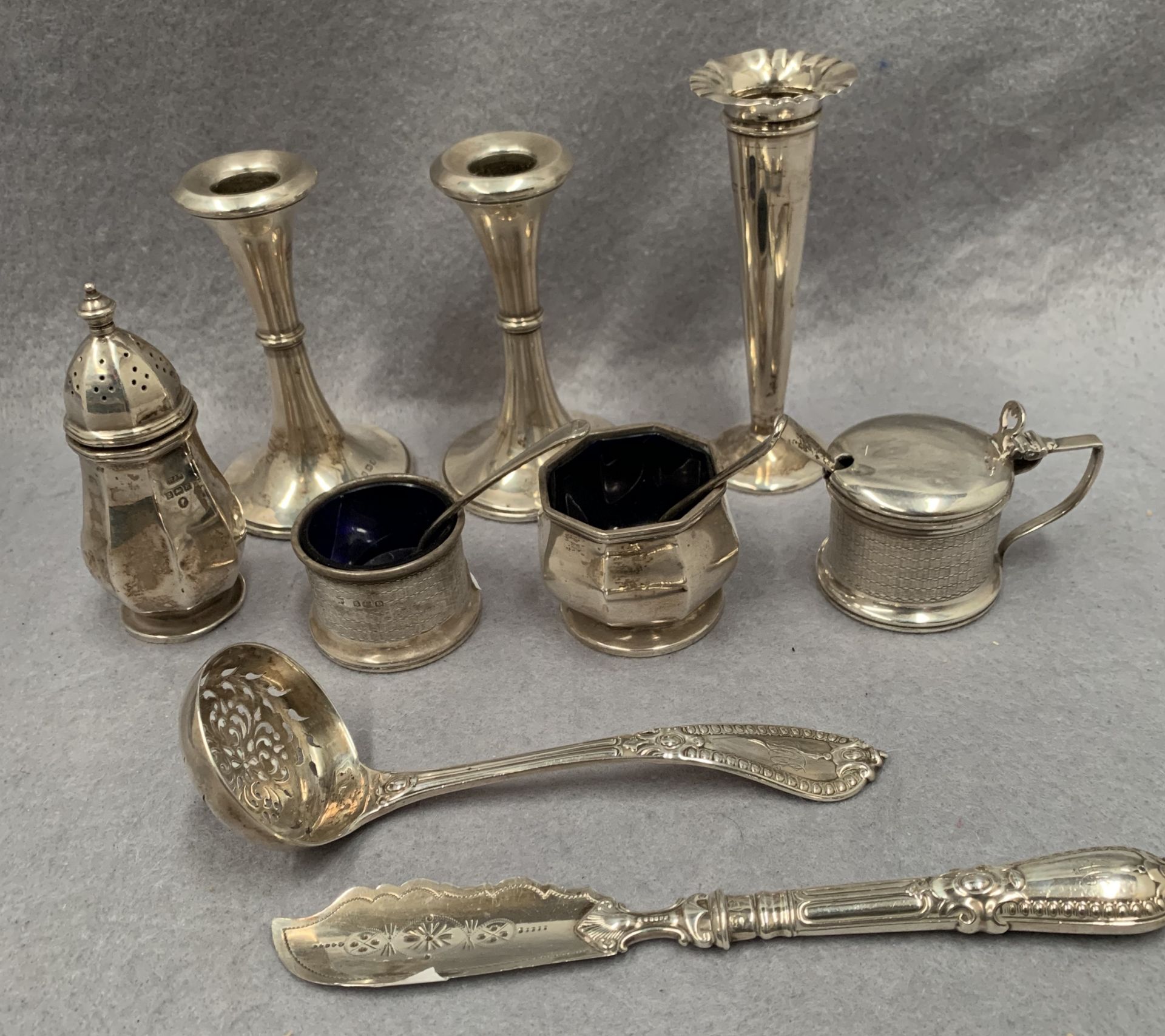 A pair of small silver candlesticks, a small silver vase, a silver mustard pot,