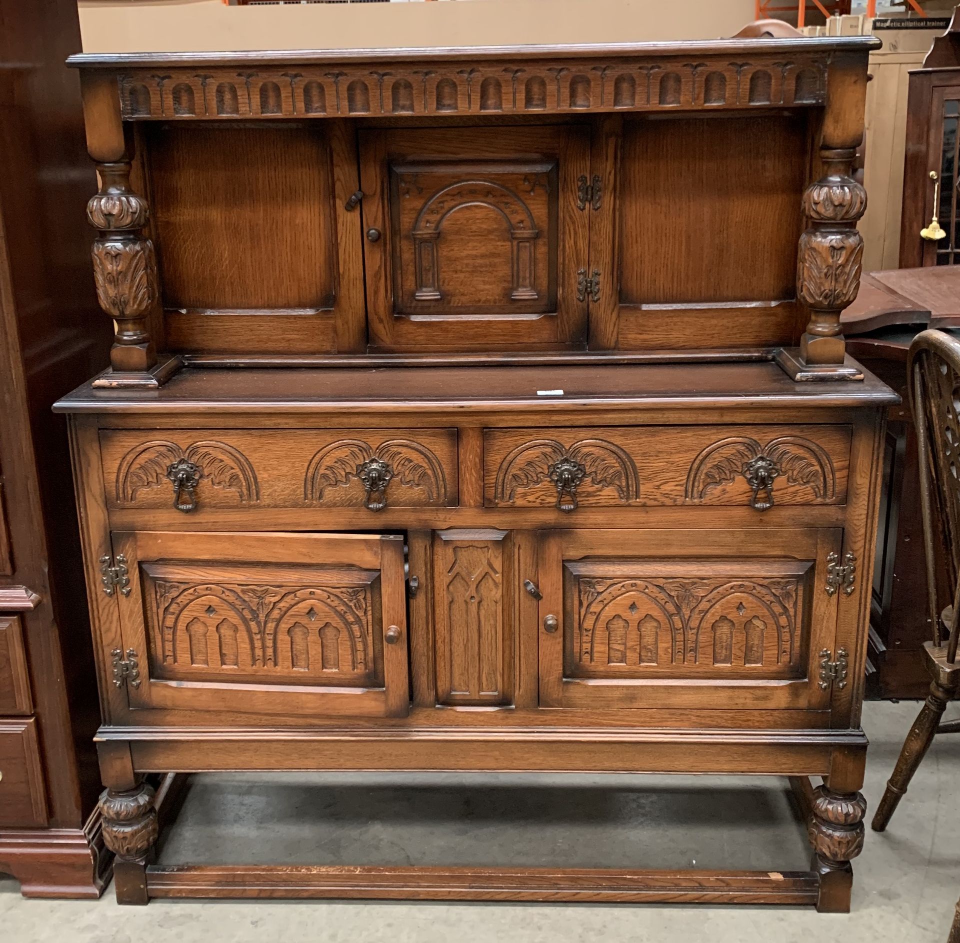 A dark oak finish sideboard/court cupboard with upper single door over two door/two drawer base,