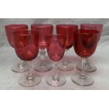 Two cranberry wine glasses with cut glass stems and four other cranberry wine glasses and one