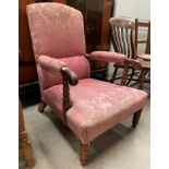 An oak framed low armchair with pink floral patterned upholstery