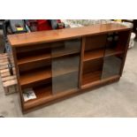 A 1950s mahogany low bookcase with glass sliding doors and 136 x 77cm high