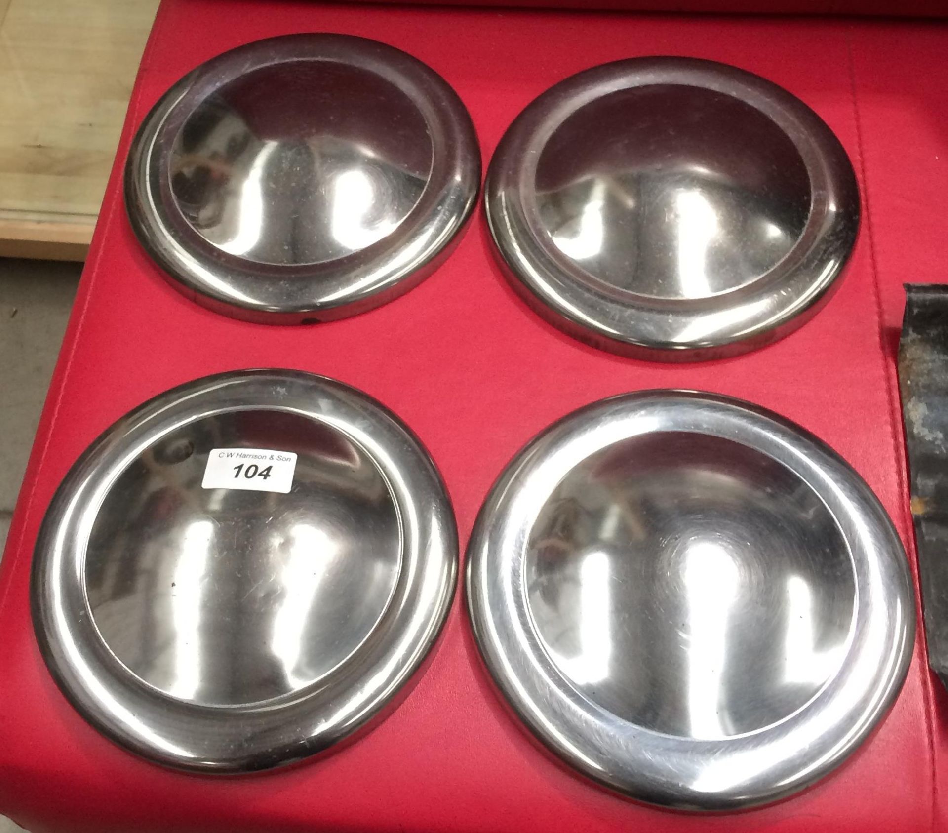 Four stainless steel hub caps for a Classic Mini