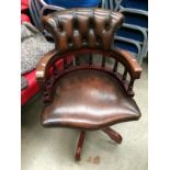 A reproduction brown leather finish swivel armchair
