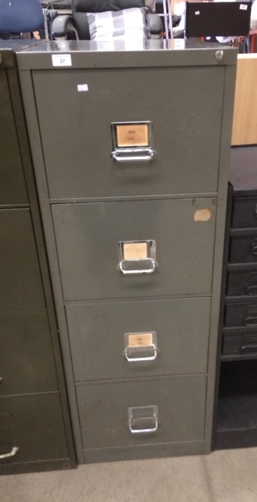 A grey metal four drawer filing cabinet complete with key