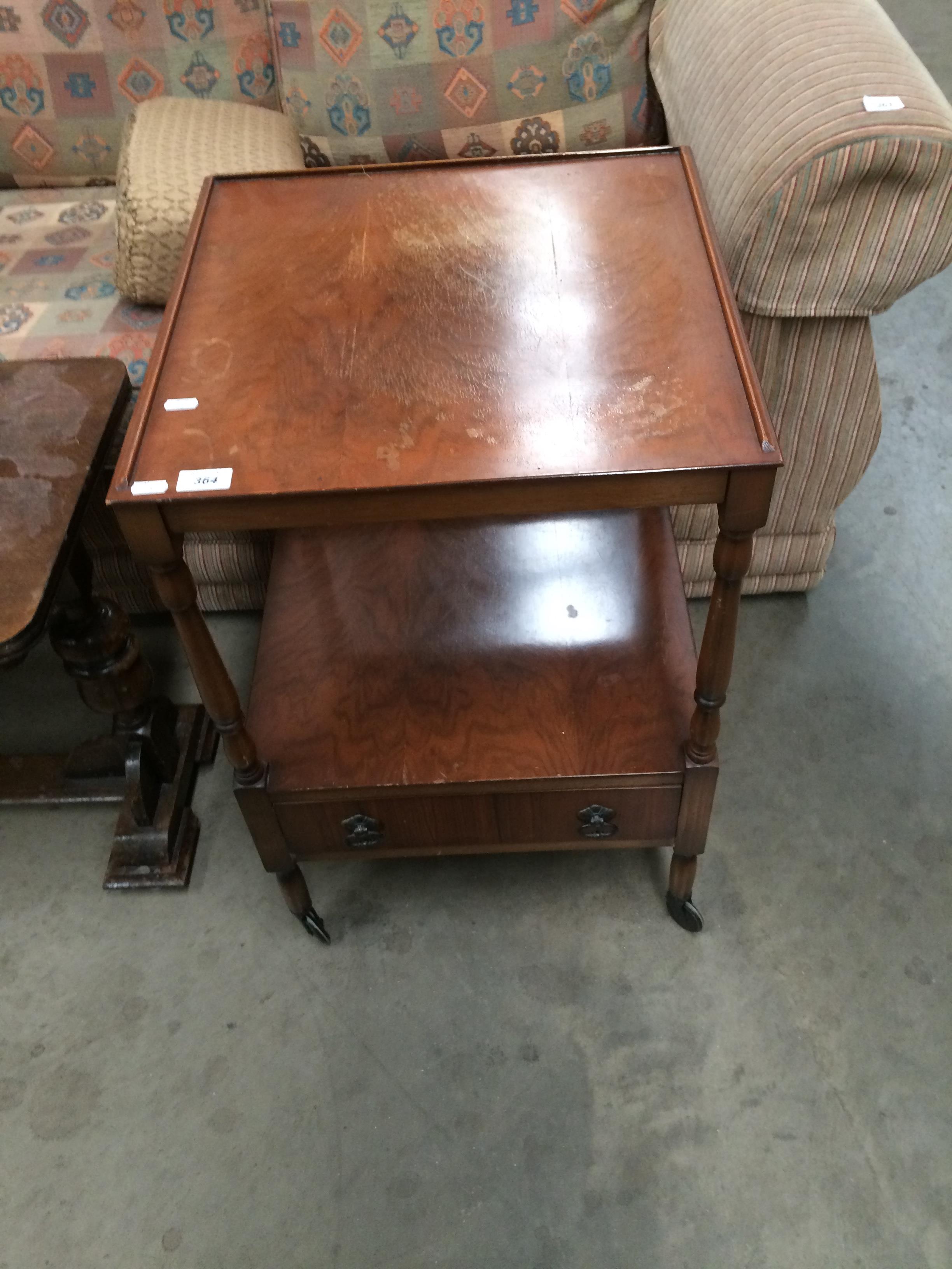 A walnut finish mobile table with undertray and single door