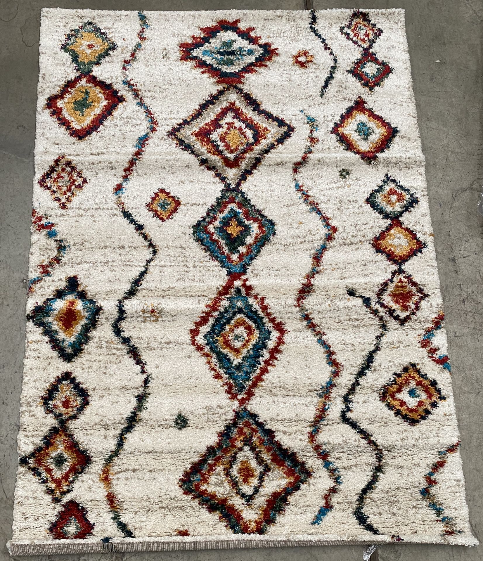 A cream and multi coloured diamond patterned rug - 160cm x 230cm