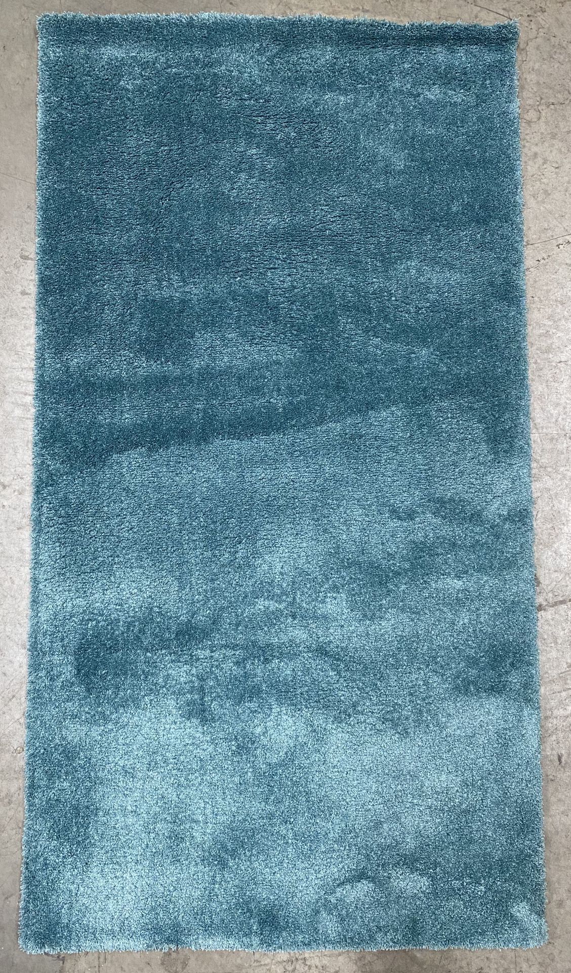 A turquoise felt backed rug - 150cm x 80cm