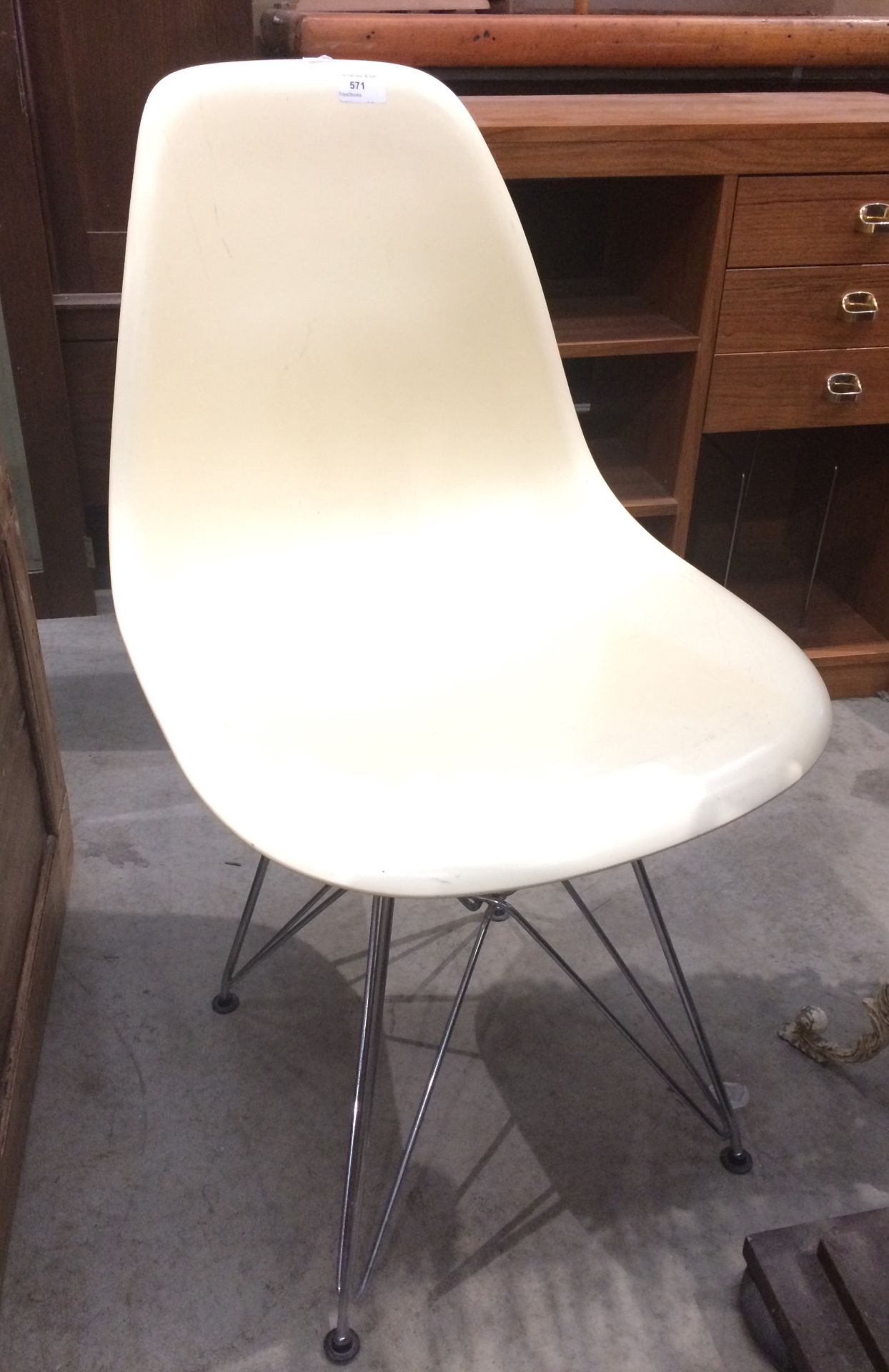 A cream plastic side chair on chrome base in the style of Eames