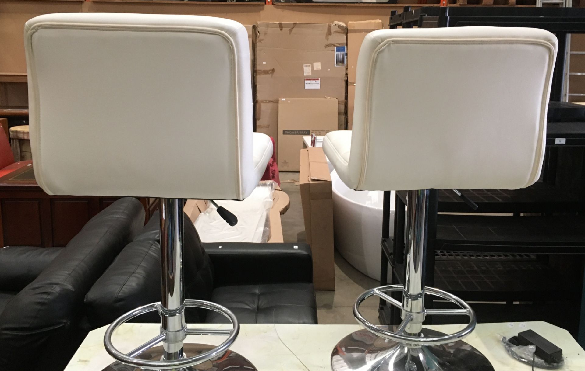 A pair of cream leather finish adjustable bar chairs on chrome revolving bases