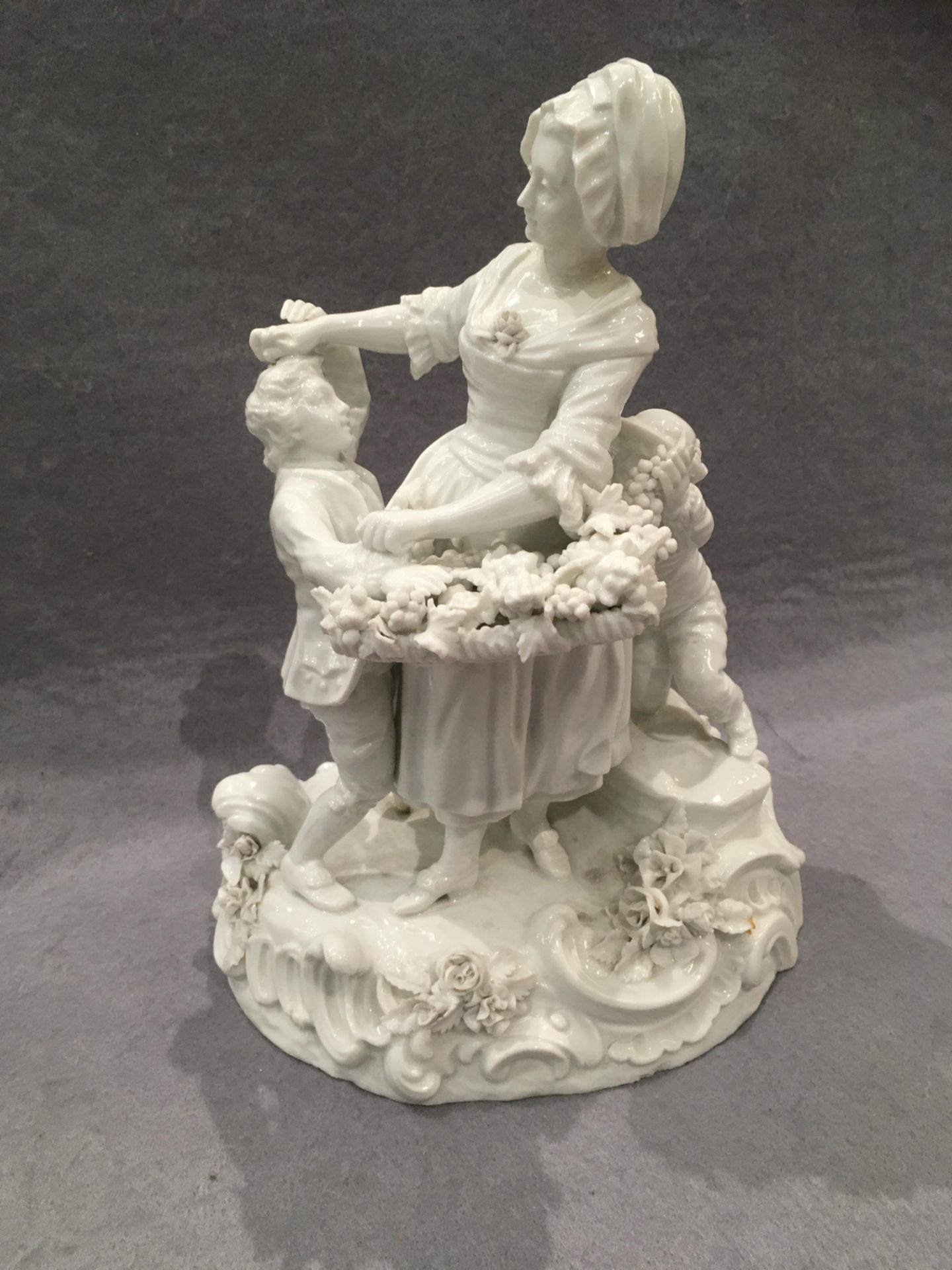 A white glazed porcelain figure group of women with basket of grapes with two children, 26cm hiugh,