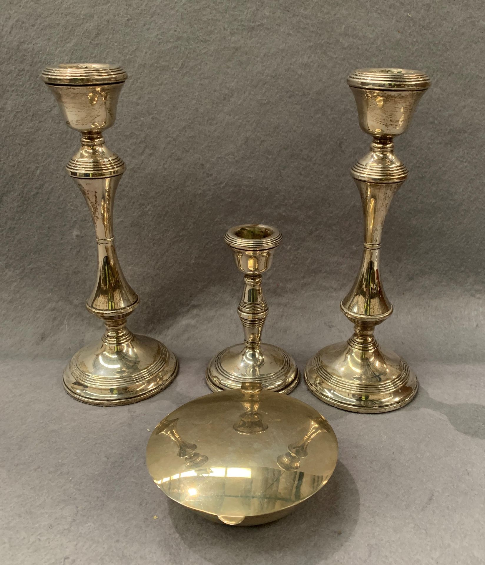 A pair of silver candlesticks, each 21cm high, a smaller silver candlestick,