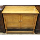 A 1920's carved light oak two door stretcher cupboard