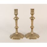 A pair of 18th Century seamed brass candlesticks with knopped stems and wide petal shaped bases,