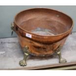 A copper and brass log bin on paw feet and lion mask handles