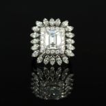 An impressive platinum diamond cluster ring, the centre emerald cut diamond approx 2.