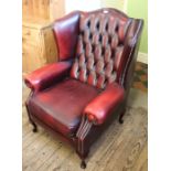 A modern Georgian style maroon leather button back wing armchair