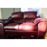 A nearly new Saxon maroon leather three piece suite, comprising a two seater sofa,