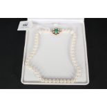 A pearl necklace with a large 9ct gold floral shaped clasp, green enamel decoration to centre,