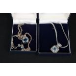 Two silver blue stone set pendants on chains,