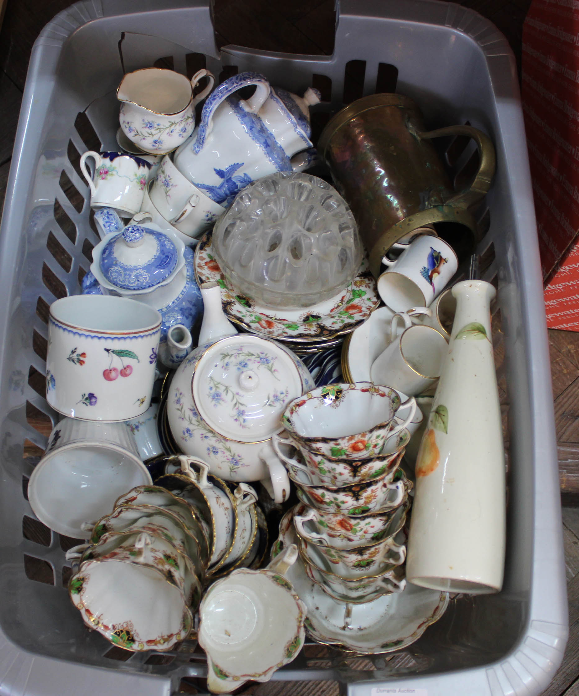 A basket containing a quantity of assorted ceramics including a part tea set and a brass tankard